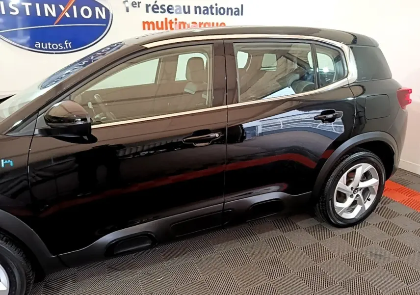 Vue latérale côté gauche d'un Citroën C5 Aircross hybride rechargeable noir brillant en intérieur showroom.