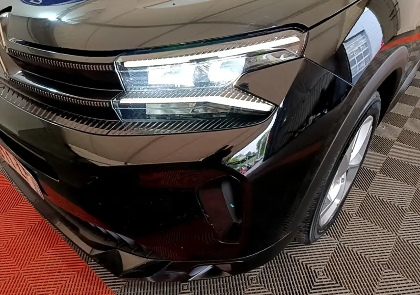 Gros plan sur l'avant droit noir brillant du Citroën C5 Aircross hybride rechargeable avec phares LED allumés.
