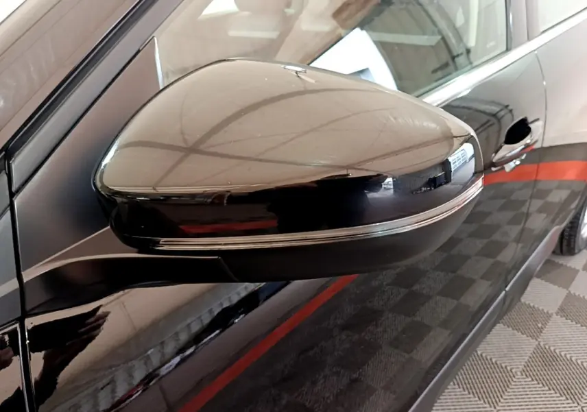 Gros plan sur le rétroviseur droit noir brillant du Citroën C5 Aircross hybride rechargeable 2022, avec reflet et porte visible.