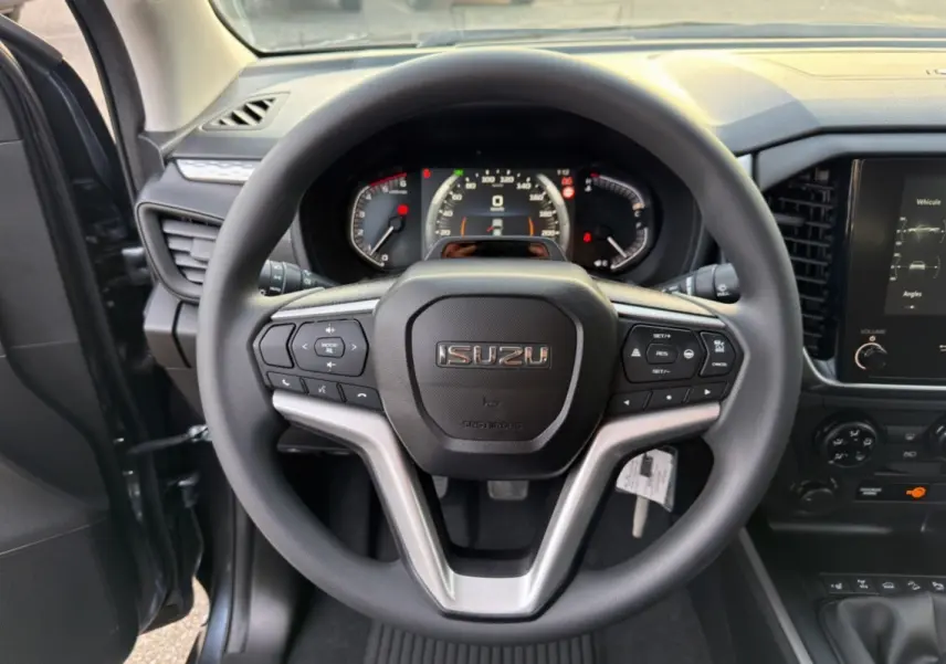 Vue centrée sur le volant multifonctions noir de l'Isuzu D-MAX 2026 avec tableau de bord et écran tactile visibles.