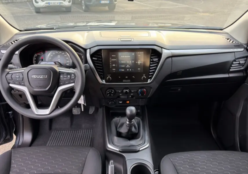 Vue intérieure avant de l'Isuzu D-MAX 2026 avec tableau de bord noir et écran tactile central.