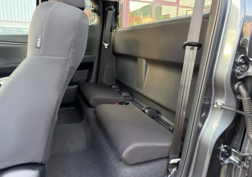 Vue latérale droite sur les sièges arrière strapontins en tissu gris du pick-up Isuzu D-MAX Obsidian Grey Mica.
