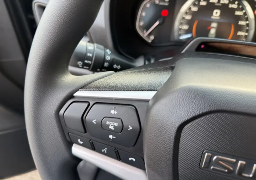 Gros plan sur le volant multifonctions noir de l'Isuzu D-MAX 2026 avec commandes audio et téléphone intégrées.