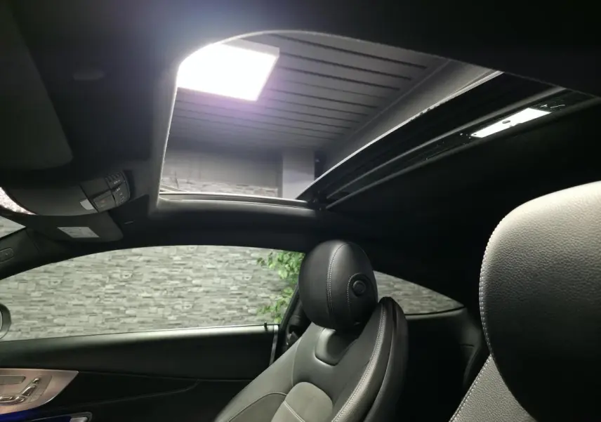 Intérieur noir du coupé Mercedes Classe C 220 d 2019, vue sur siège avant droit et toit ouvrant panoramique ouvert.