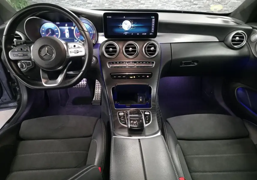 Vue intérieure avant de la Mercedes Classe C Coupé 2019, tableau de bord noir avec écran digital et volant multifonction.