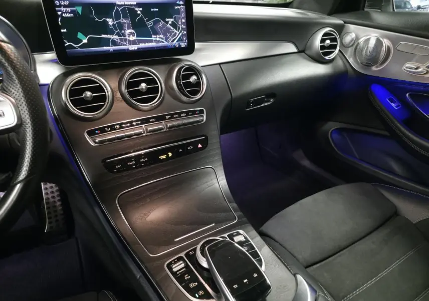 Vue intérieure côté passager de la Mercedes Classe C Coupé AMG Line 2019, avec éclairage d'ambiance bleu et finitions noires.