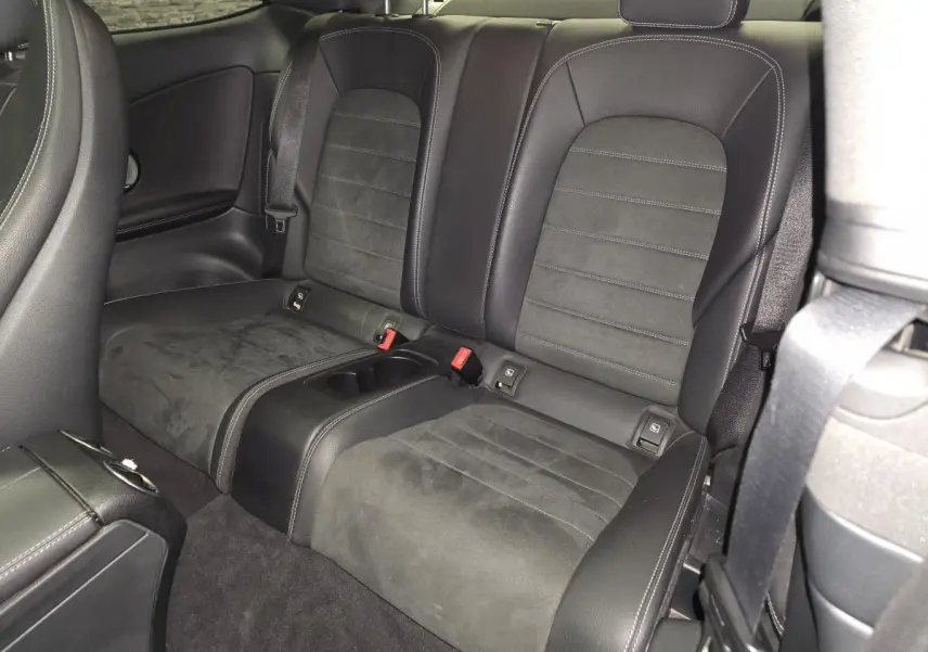 Vue intérieure arrière montrant les sièges en cuir noir et alcantara du coupé Mercedes Classe C gris.