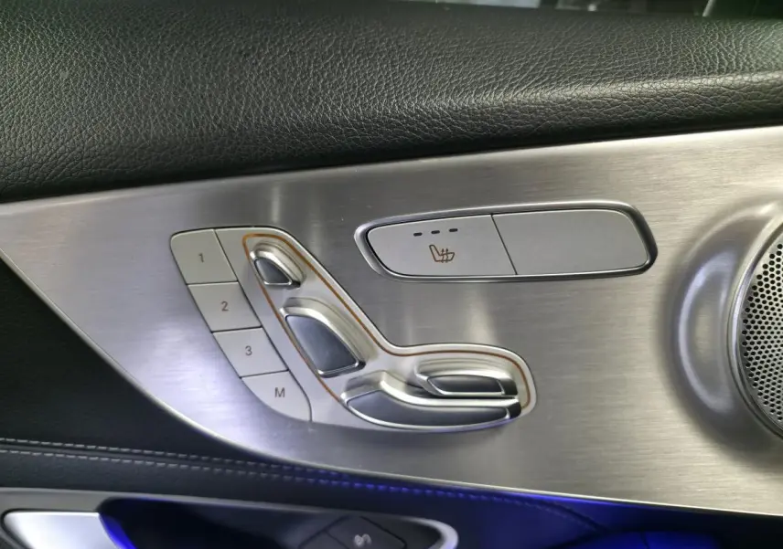 Détail du panneau de porte côté gauche en aluminium brossé avec commandes de siège chauffant et mémoire sur Mercedes Classe C Coupé gris.