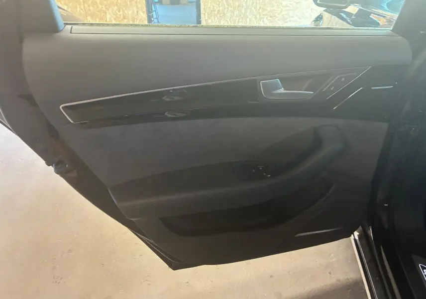Vue intérieure de la porte arrière droite noire d'une Audi A8 2016 avec garniture en cuir et inserts brillants.