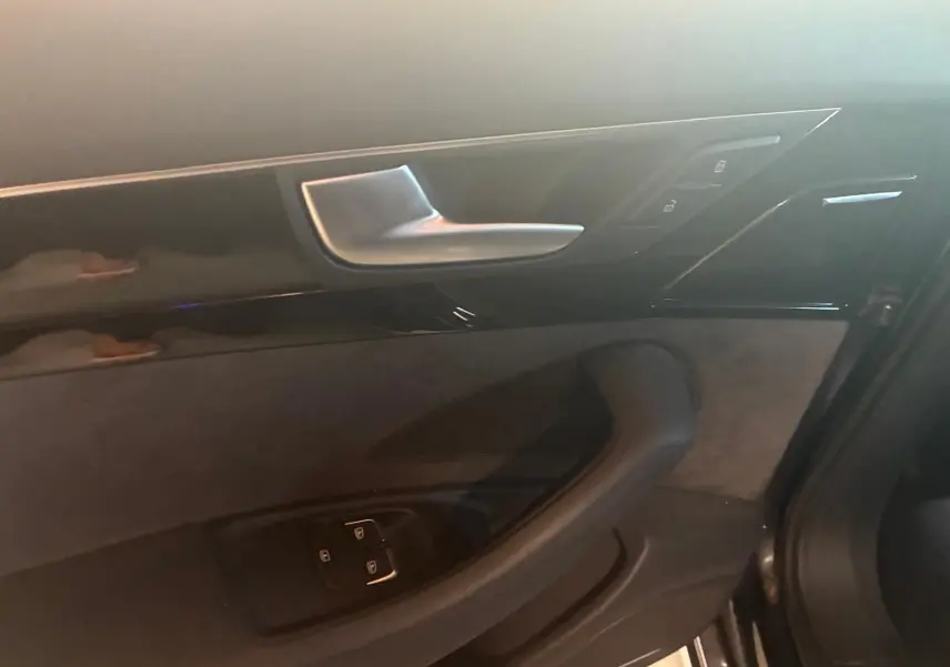 Détail de la porte intérieure côté gauche de l’Audi A8 noire 2016, avec commandes de verrouillage et poignée argentée.