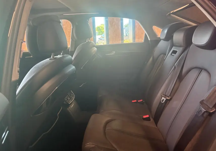 Vue intérieure arrière droite de l'Audi A8 2016 noire, montrant les sièges arrière en cuir et les ceintures de sécurité.