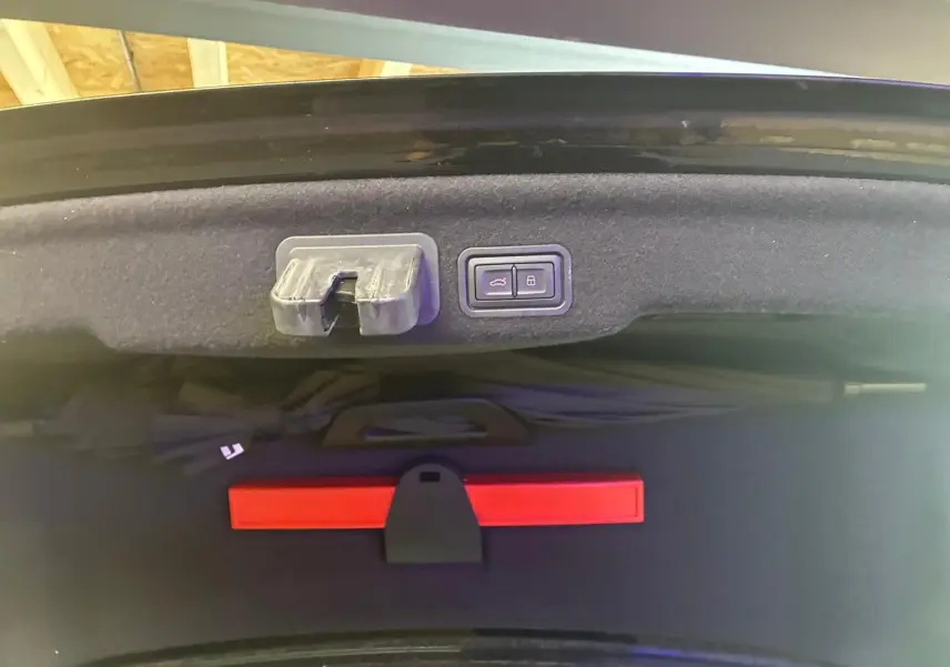 Détail intérieur du coffre de l'Audi A8 2016 noir, montrant les boutons d'ouverture et verrouillage du hayon.