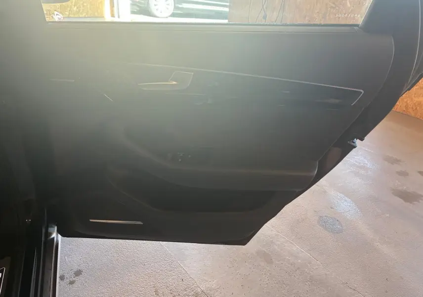 Vue intérieure de la porte avant gauche noire d'une Audi A8 2016, avec garniture en cuir et commandes de fenêtre.