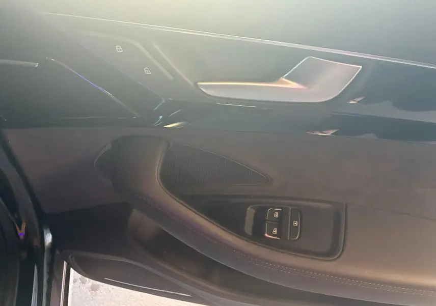 Détail de la porte intérieure côté conducteur de l’Audi A8 noire 2016 avec commandes de verrouillage et poignée argentée.