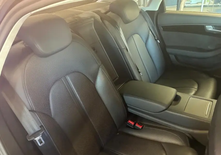 Vue intérieure côté droit des sièges arrière en cuir noir de l'Audi A8 2016 avec accoudoir central et ceintures visibles.