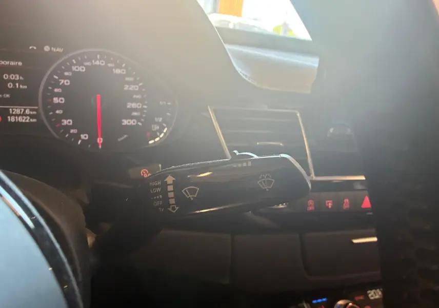 Gros plan sur la manette d'essuie-glace à gauche du volant dans l'habitacle noir de l'Audi A8 2016.
