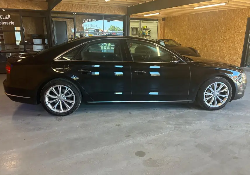 Audi A8 3.0 TDI 2016 noir vue de profil côté gauche, avec jantes alliage et intérieur visible en atelier.