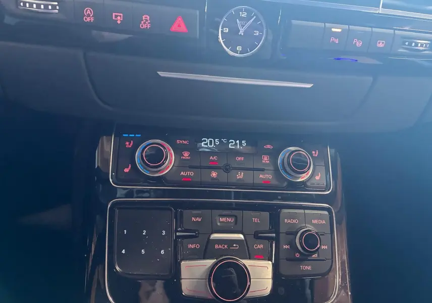 Vue rapprochée du tableau de bord noir de l'Audi A8 3.0 TDI 2016, avec horloge analogique et commandes climatisation digitales.