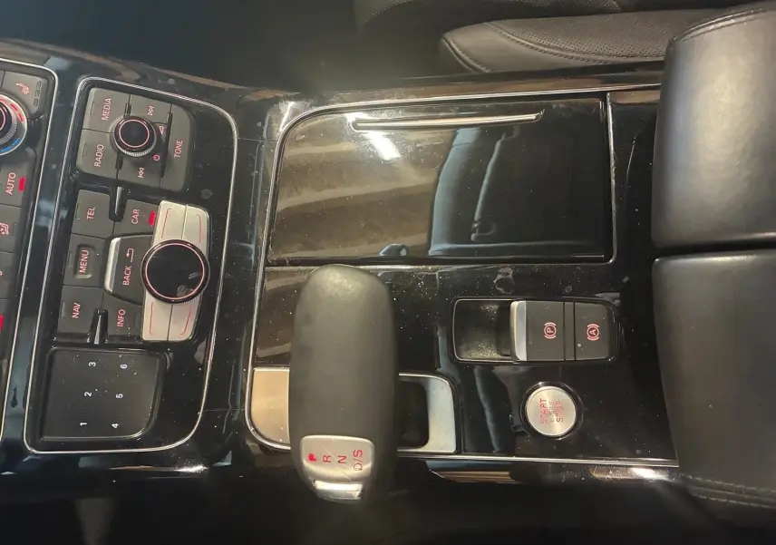 Vue rapprochée du levier de vitesses automatique et des commandes centrales noires de l’Audi A8 3.0 TDI 2016.