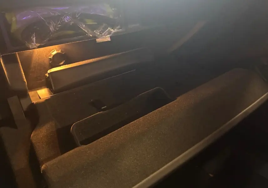 Intérieur du coffre noir d’une Audi A8 2016, vue en plongée avec éclairage tamisé sur la moquette et rangement.