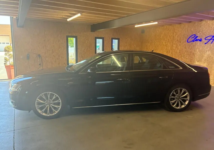 Audi A8 3.0 TDI noire vue de profil côté gauche, stationnée en intérieur avec jantes alliage distinctives.