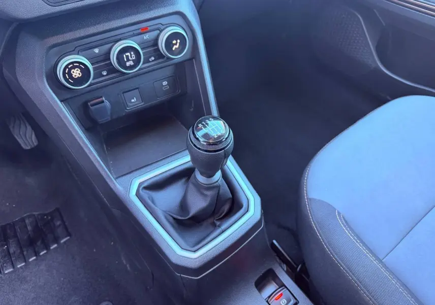 Gros plan sur la console centrale d'une Dacia Sandero 2025, levier de vitesses manuel et commandes climatisation visibles.