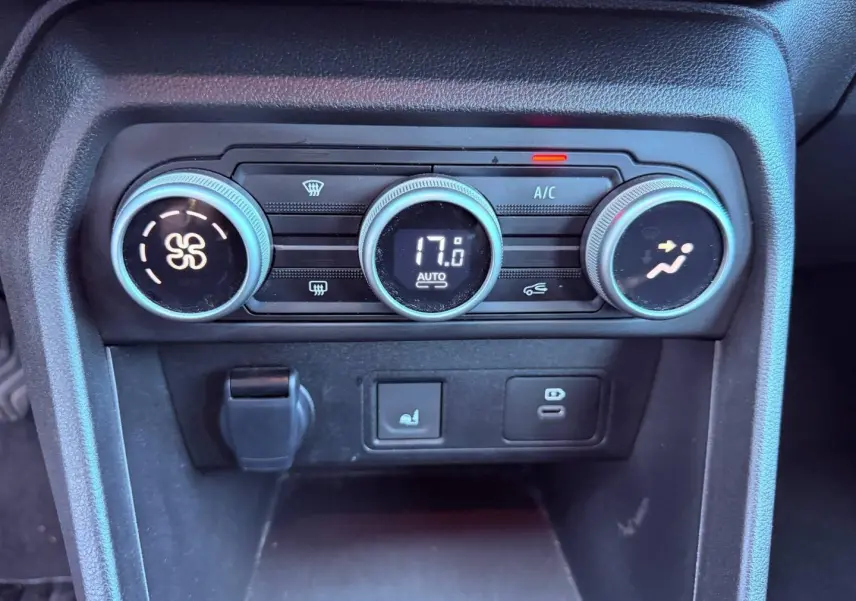 Vue rapprochée des commandes de climatisation automatique de la Dacia Sandero 2025, boutons ronds noirs avec affichage digital.
