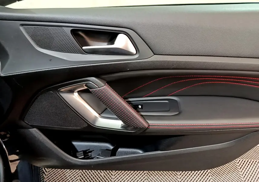 Détail de la porte côté conducteur de la Peugeot 308 GT Line 2016, avec surpiqûres rouges et poignée en cuir noir.