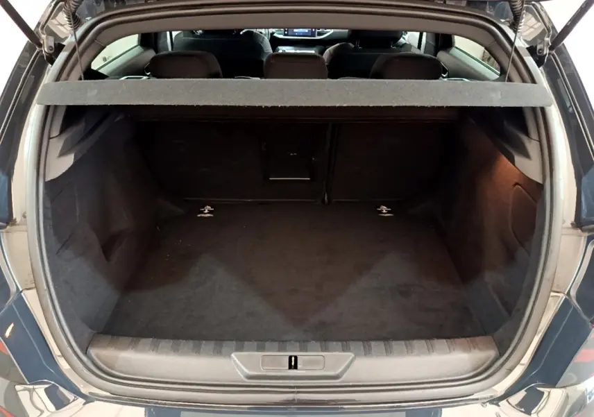 Coffre ouvert vu de l'arrière d'une Peugeot 308 gris foncé, montrant la banquette arrière et la trappe à ski.