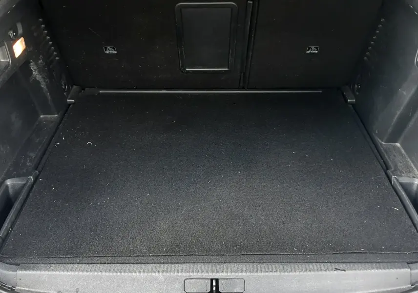 Coffre ouvert vu de face d’un Peugeot 3008 gris Amazonite, espace de chargement propre et tapis noir.