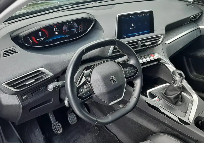 Vue intérieure côté conducteur du Peugeot 3008 gris Amazonite, avec volant compact, tableau de bord digital et boîte manuelle.