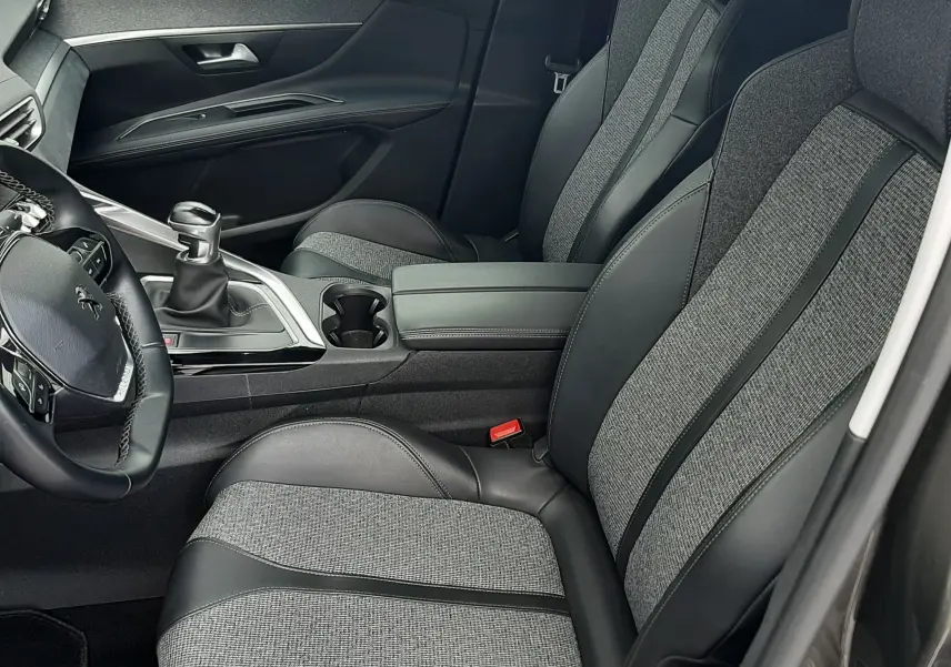 Vue intérieure côté conducteur du Peugeot 3008 2019, sièges tissu et cuir gris avec console centrale et levier de vitesse manuel.