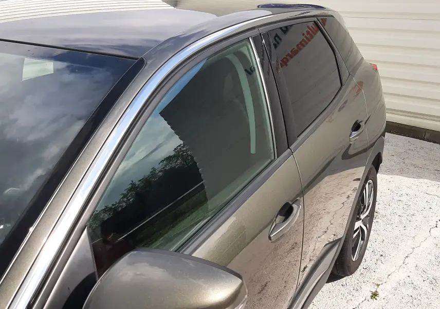 Vue 3/4 avant côté gauche du Peugeot 3008 gris amazonite avec rétroviseur et jantes visibles.