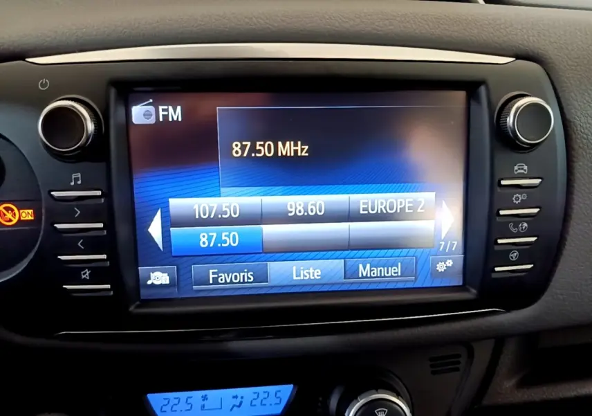 Écran tactile central de la Toyota Yaris blanche 2019 affichant la radio FM et commandes multimédia.