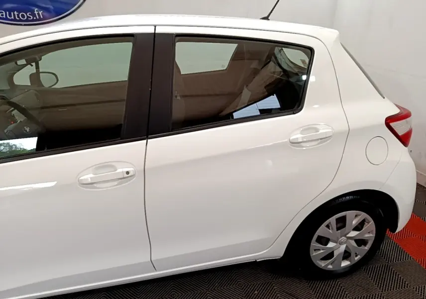 Vue latérale droite d'une Toyota Yaris blanche 2019, mettant en valeur les portières arrière et avant avec poignées intégrées.