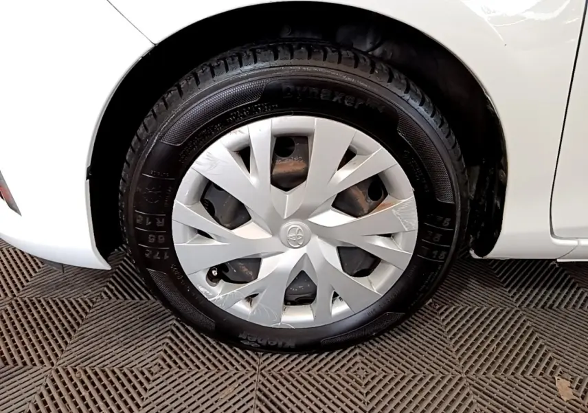 Gros plan sur la roue avant gauche blanche d'une Toyota Yaris 2019 avec enjoliveur argenté et pneu noir.