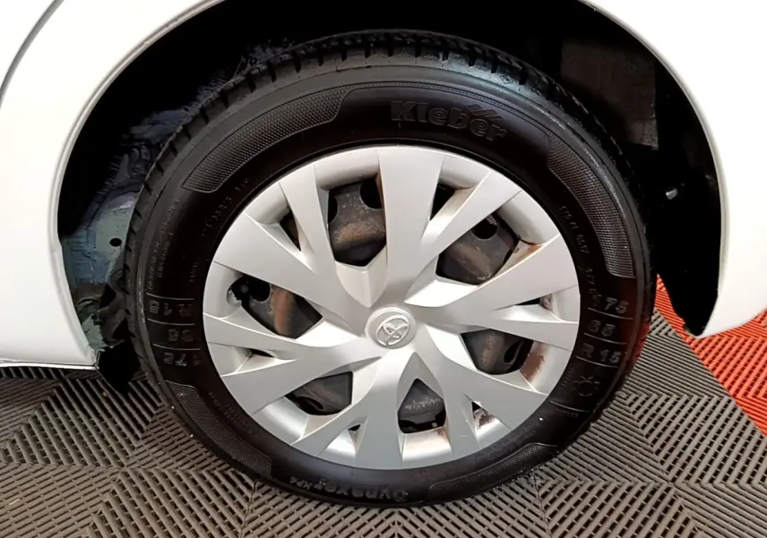 Gros plan sur la roue avant gauche blanche d'une Toyota Yaris 110 VVT-i CVT France Business avec enjoliveur argenté.