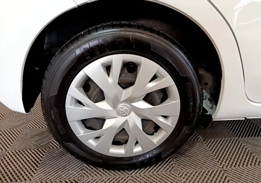 Gros plan sur la roue arrière droite blanche d'une Toyota Yaris 2019 avec enjoliveur argenté au design épuré.