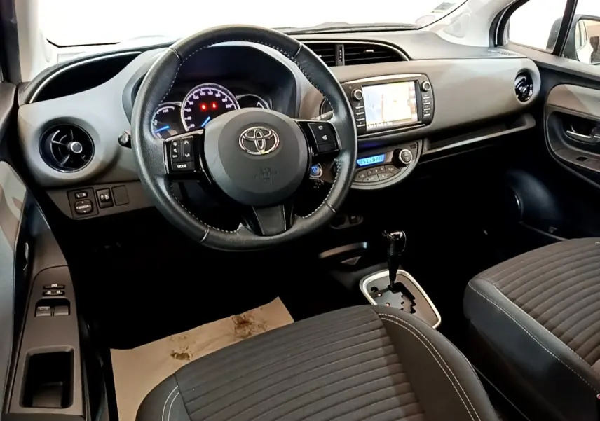 Vue intérieure avant droite de la Toyota Yaris 2019, volant cuir multifonctions et écran tactile de navigation visible.