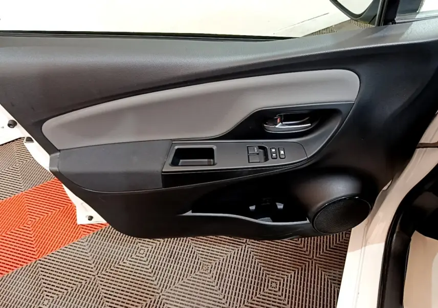 Vue intérieure de la porte avant gauche blanche de la Toyota Yaris 2019, avec commandes électriques et haut-parleur intégré.