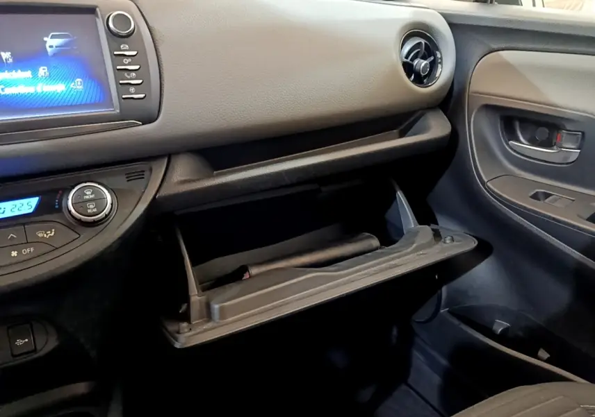Intérieur noir de la Toyota Yaris 2019, vue côté passager avec boîte à gants ouverte et écran tactile allumé.