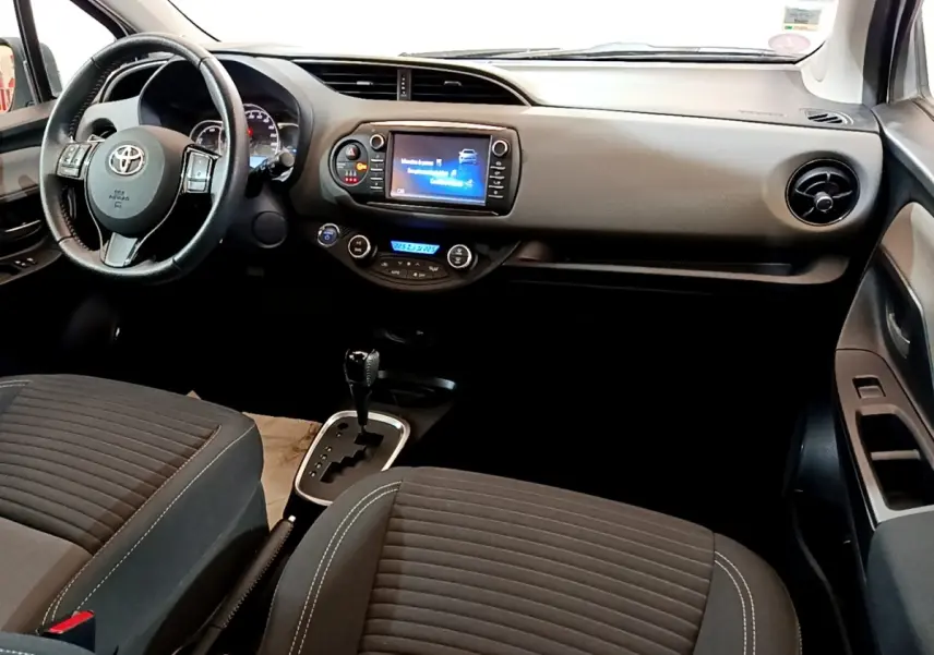 Vue intérieure avant droite de la Toyota Yaris 2019, volant cuir multifonctions et écran tactile central allumé.