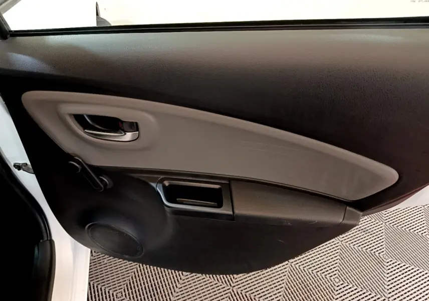 Vue intérieure côté gauche de la porte avant blanche d'une Toyota Yaris 2019 avec poignée et haut-parleur intégrés.