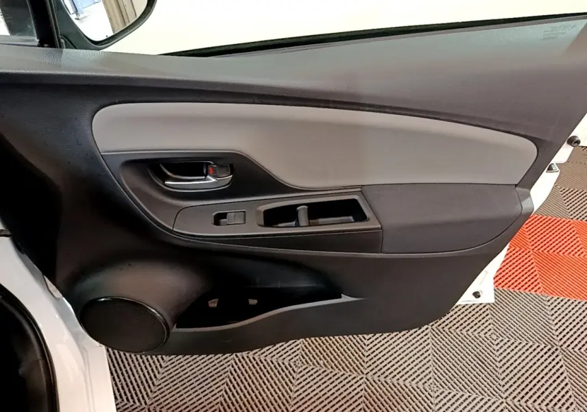 Vue rapprochée de la porte avant gauche blanche de la Toyota Yaris 2019 avec panneau intérieur noir et gris.
