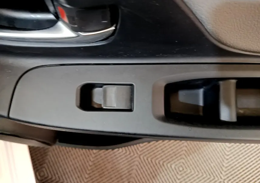 Détail de la commande de lève-vitre côté conducteur dans l’habitacle noir de la Toyota Yaris blanche 2019.