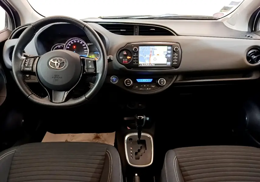 Vue intérieure avant de la Toyota Yaris 2019, tableau de bord noir avec écran tactile et volant multifonctions cuir alu.