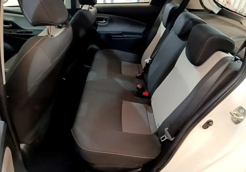 Vue intérieure arrière droite de la Toyota Yaris blanche 2019, montrant la banquette bi-ton noire et grise avec appuie-têtes.