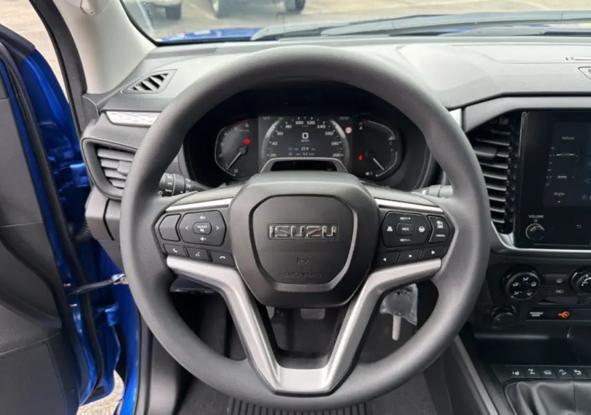 Vue centrée sur le volant multifonctions d’un Isuzu D-MAX bleu Biarritz, avec tableau de bord et écran tactile visibles.
