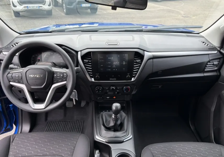Vue intérieure frontale de l'Isuzu D-MAX bleu Biarritz, montrant le volant multifonctions et la console centrale avec écran tactile.