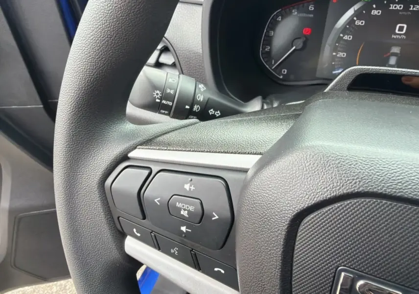 Gros plan sur le volant multifonctions côté gauche de l’Isuzu D-MAX 2026 Biarritz blue metalic, avec commandes audio visibles.